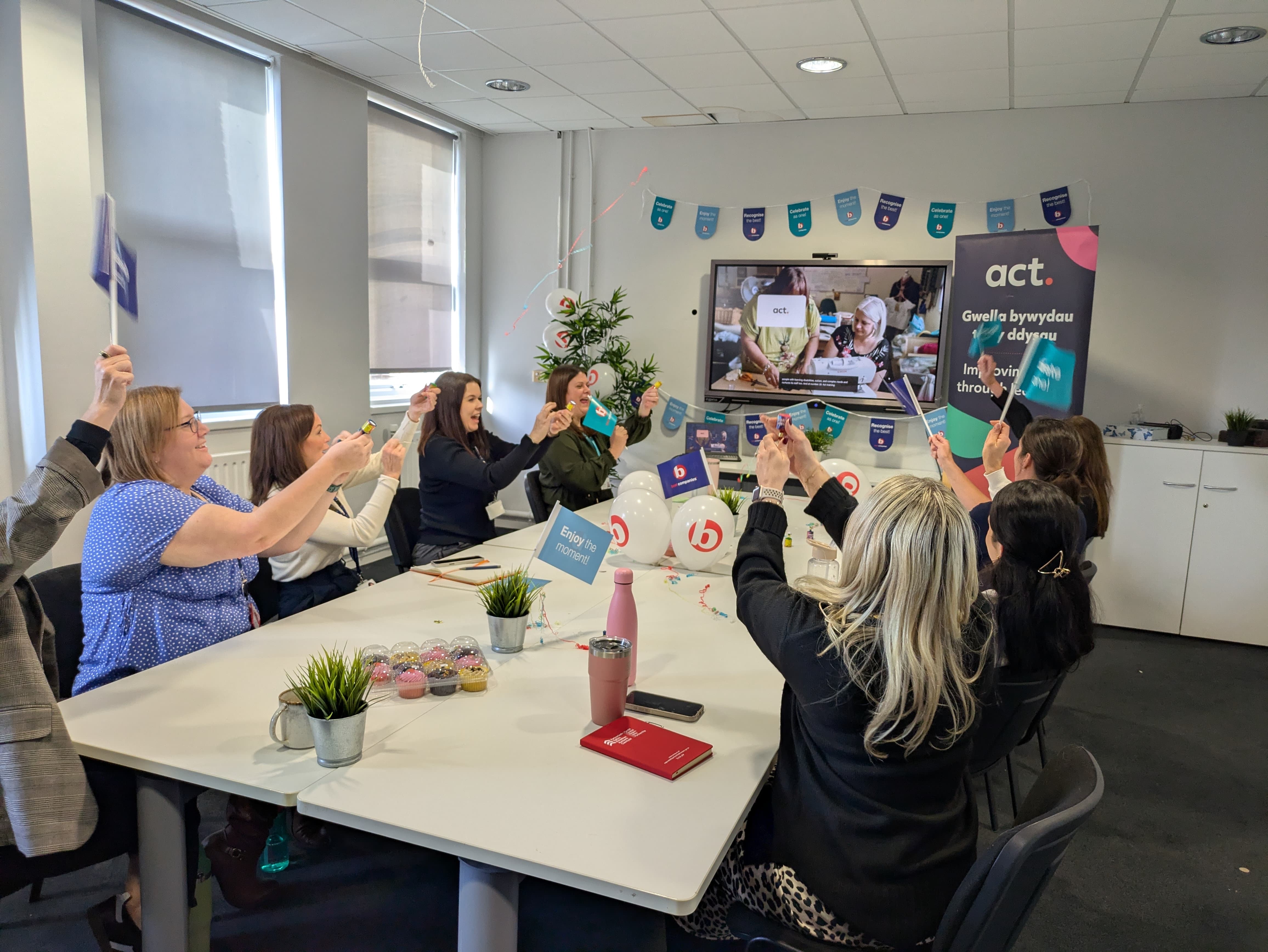 Team of colleagues popping party poppers around a desk
