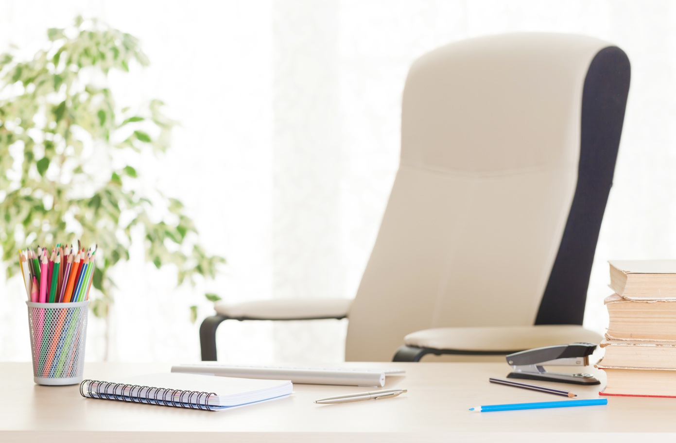 An empty desk chair with stationary on the desk